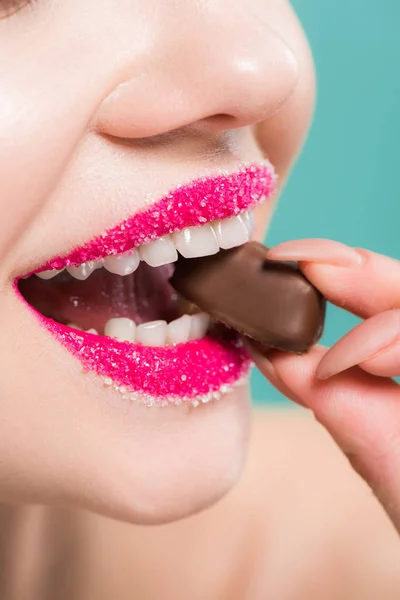 青で隔離されたチョコレートキャンディを食べる幸せな女性のトリミングされたビュー — ストック写真