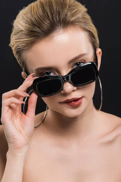 Atractiva Joven Mordiendo Labios Mientras Toca Gafas Sol Aisladas Negro — Foto de Stock