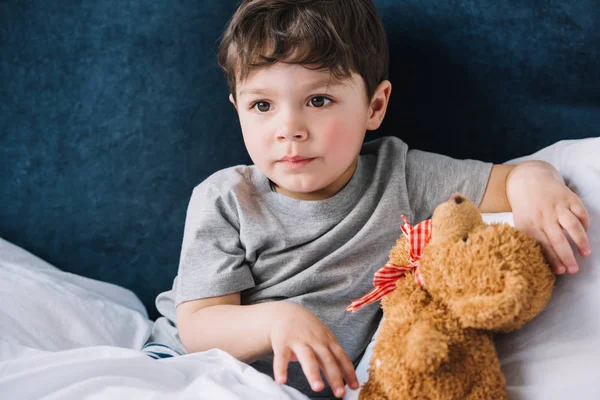 Niedliche Kind Sitzt Neben Teddybär Schlafzimmer Hause — Stockfoto