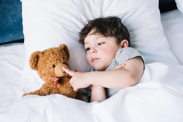 Entzückendes Kind Liegt Auf Weißem Kissen Und Berührt Teddybär Hause — Stockfoto