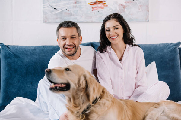 selective focus of happy man and woman near cute golden retriever in bedroom 
