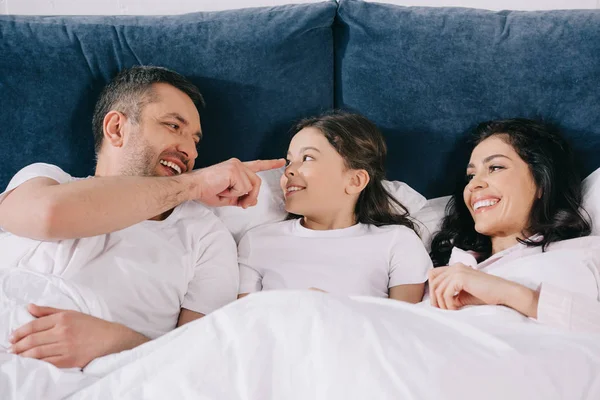 Alegre Padre Señalando Con Dedo Nariz Linda Hija Cerca Esposa — Foto de Stock