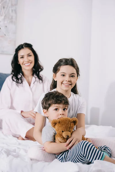 寝室で幼児の兄弟と陽気な母親の近くに幸せな子供の選択的な焦点 — ストック写真