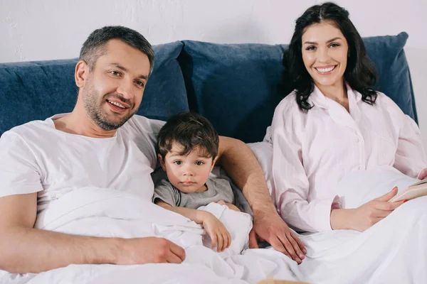 Feliz Padre Sonriendo Cerca Niño Hijo Atractiva Esposa Dormitorio — Foto de Stock