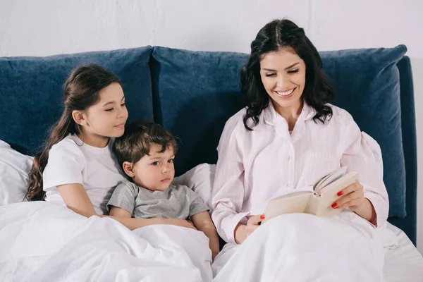 Весела Мама Читає Книгу Біля Милої Дочки Сина Спальні — стокове фото