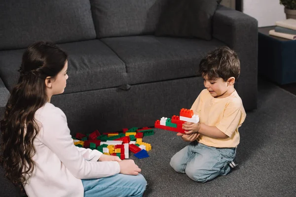 Niedliches Kind Schaut Auf Kleinkind Bruder Spielt Mit Bunten Spielzeugklötzen — Stockfoto