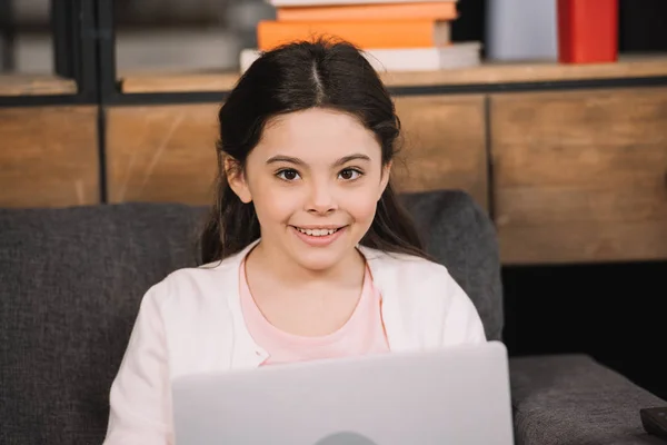 Mutlu Çocuk Oturma Odasında Dizüstü Bilgisayar Yakınında Kamera Bakıyor — Stok fotoğraf