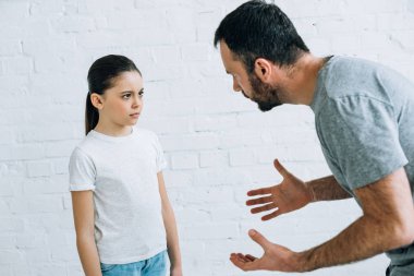 bearded angry father scolding upset daughter at home clipart