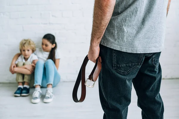Vista Recortada Padre Abusivo Sujetando Cinturón Niños Tristes Sentados Suelo — Foto de Stock