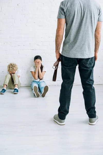 Cropped View Abusive Father Holding Belt Scared Kids Sitting Floor — Stock Photo, Image