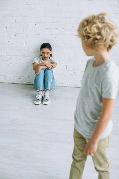 床に座っている妹を見ている十代の少年 — ストック写真