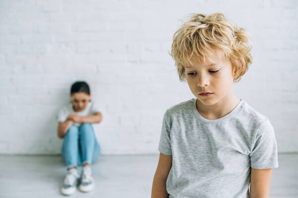 грустный младший брат и сестра в футболках дома
