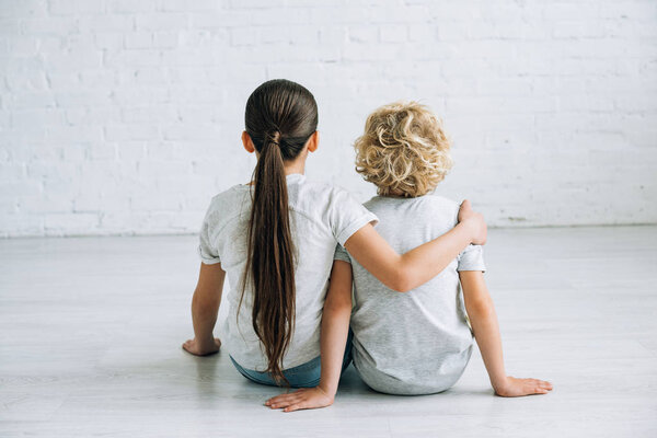 back view of two kids embracing on floor at home