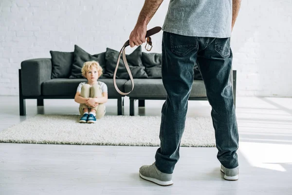 Partial View Abusive Father Holding Belt Sad Son Sitting Carpet — Stock Photo, Image