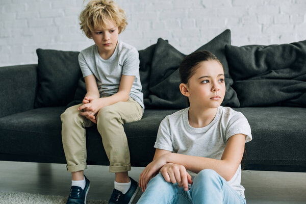 sad sister and brother on sofa in living room