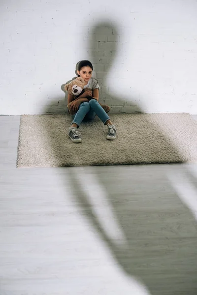 Niño Asustado Con Oso Peluche Sentado Alfombra Silueta Grande — Foto de Stock