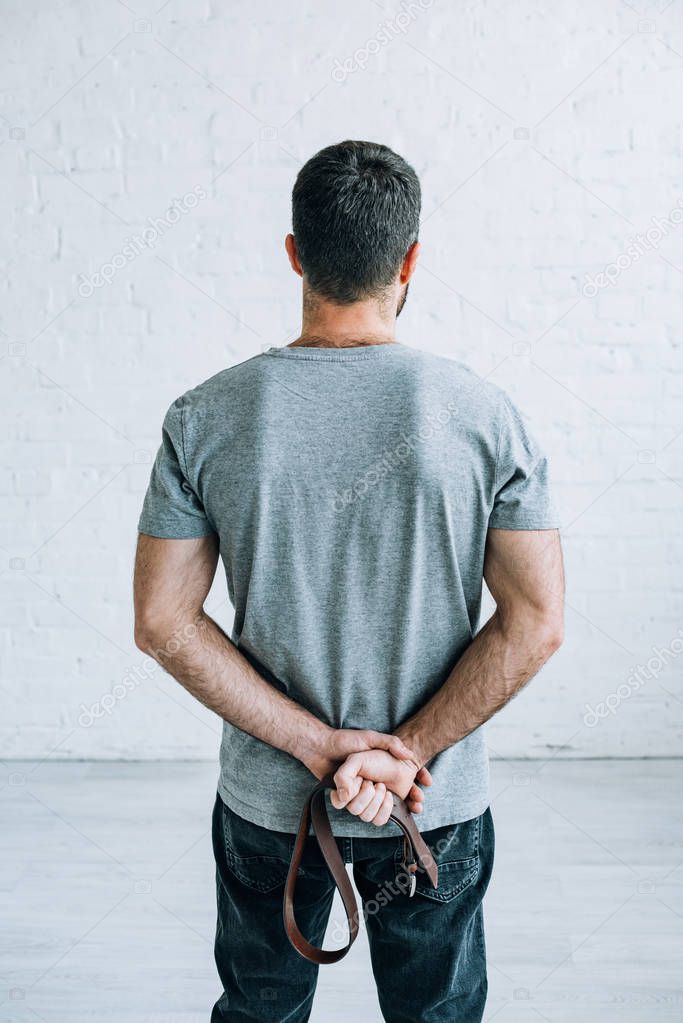 back view of man holding belt at home