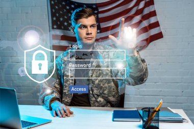 handsome soldier in uniform pointing with finger at login and password lettering in office  clipart