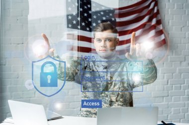 handsome soldier in military uniform pointing with fingers at virtual access in office  clipart