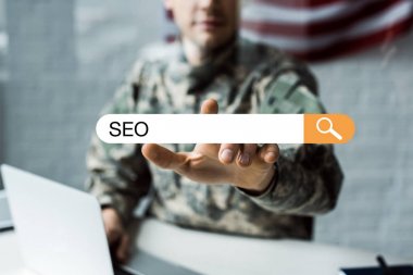 selective focus of man in military uniform pointing with finger at address bar with seo lettering  clipart
