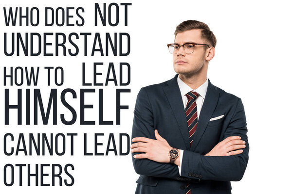 handsome businessman standing with crossed arms near who doesn't understand how to lead himself cannot lead others lettering on white 