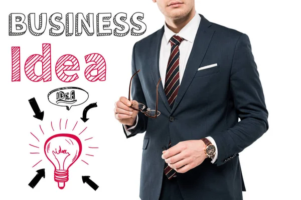 スーツを着たビジネスマンが ビジネスのアイデアの文字を白に書き込む近くに眼鏡をかけている様子を見る — ストック写真
