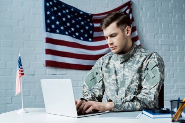 young soldier in uniform using laptop in office 