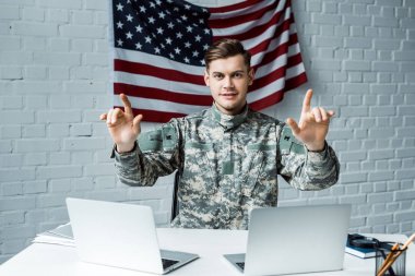 ofiste dizüstü bilgisayarlar yakınında gesturing üniformalı mutlu asker 