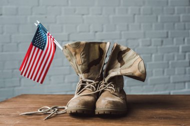 military boots and american flags with stars and stripes on wooden surface  clipart