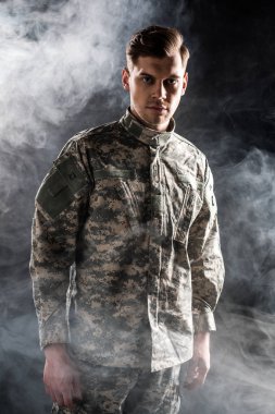 handsome man in military uniform looking at camera on black with smoke  clipart