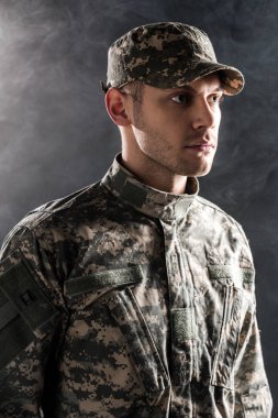 serious soldier in military uniform and cap on black with smoke  clipart