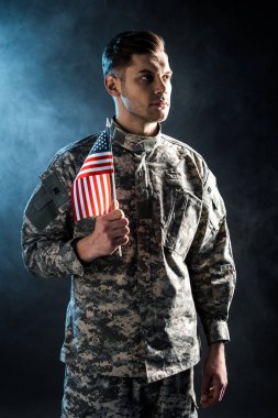 askeri üniformalı kendinden emin asker duman ile siyah amerikan bayrağı tutan 