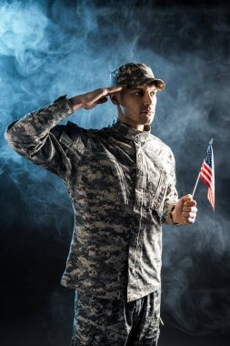 amerikan bayrağı tutan ve duman ile siyah selam veren askeri üniformalı emin asker 