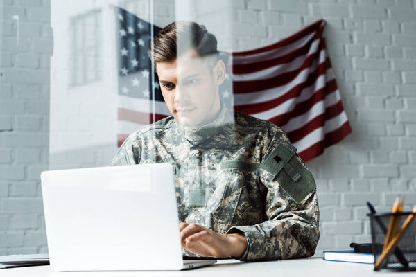 handsome soldier in camouflage uniform using laptop in office 