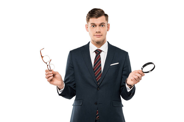 surprised businessman holding glasses and magnifying glass isolated on white 