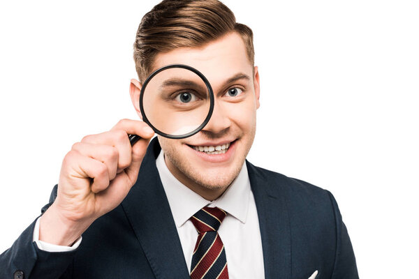 cheerful businessman holding magnifying glass near eye isolated on white 