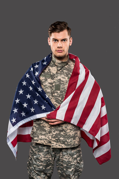 handsome man in military uniform with american flag isolated on grey 