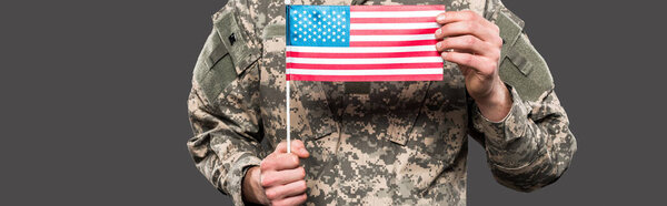 panoramic shot of soldier holding american flag isolated on grey 