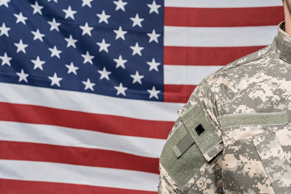 cropped view of soldier in military uniform near flag of america