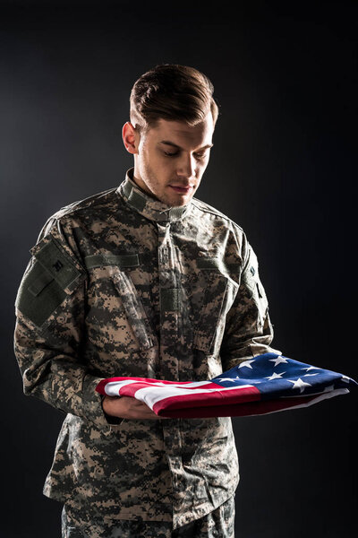 man in military uniform looking at american flag on black 