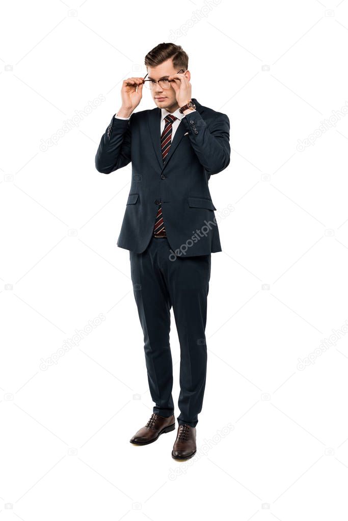 businessman in suit touching glasses and standing isolated on white 