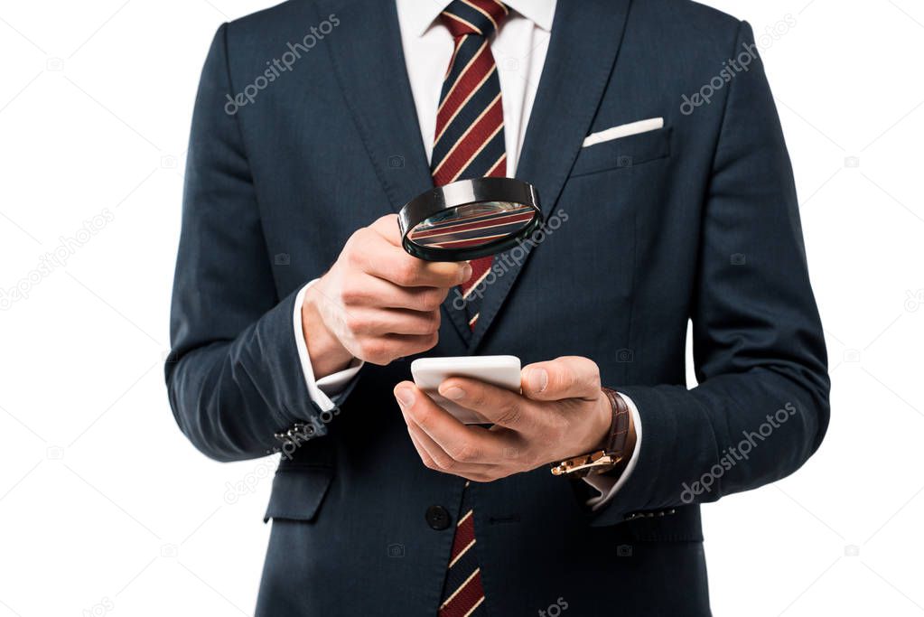 cropped view of businessman holding magnifying glass near smartphone isolated on white 