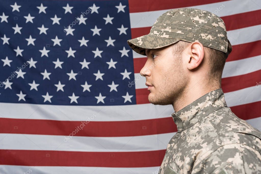 Hombre serio en uniforme militar, sosteniendo la bandera americana sobre  gris Fotografía de stock - Alamy