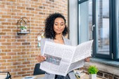 atraktivní africká americká příležitostná žena čtení obchodních novin v podkrovní kanceláři