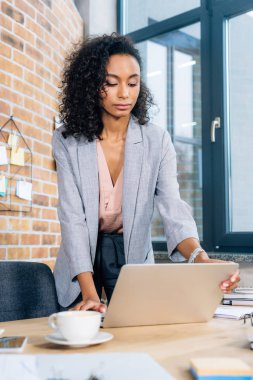 ofis masasında dizüstü bilgisayar kullanarak güzel afrikalı amerikalı Casual iş kadını