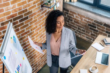 loft ofisinde flipchart yakın kağıtları tutan afrikalı amerikalı Casual iş kadını