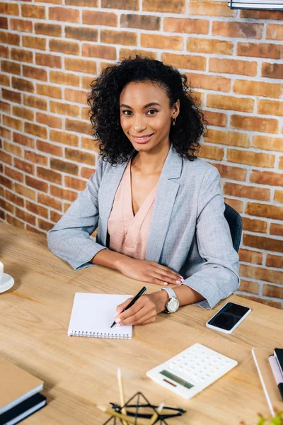 Mosolygó Afro Amerikai Alkalmi Üzletasszony Írásban Notebook Pultnál Loft Office — Stock Fotó