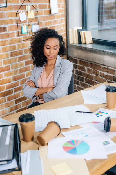 african american Casual businesswoman at desk with coffee to go cups and charts in office