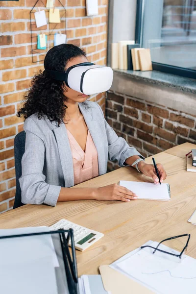 African American Casual Businesswoman Virtual Reality Headset Writing Notebook Office — Stock Photo, Image