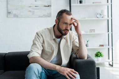 evde kanepede oturan rahatsız sakallı ve yakışıklı adam 